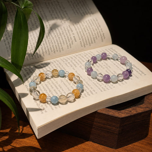 Two crystal bracelets with blue, amber, and clear beads laid on an open book