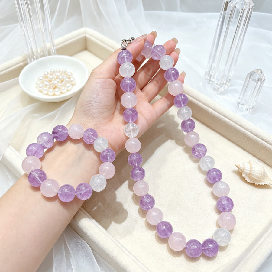 Hands holding lilac amethyst-and-quartz beaded necklace and bracelet set