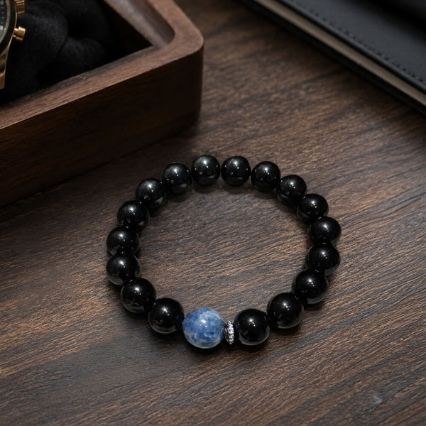 Black beaded bracelet with blue crystal centerpiece on tabletop