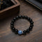 Black beaded bracelet with blue crystal centerpiece on tabletop