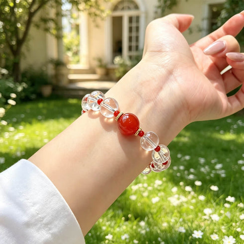 Clear quartz crystal bracelet worn on wrist, with red center stone and red bead spacers