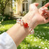 Clear quartz crystal bracelet worn on wrist, with red center stone and red bead spacers