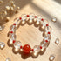 Clear quartz crystal bracelet with red center stone, surrounded by clear faceted beads
