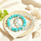 Turquoise and clear crystal bead bracelets arranged on fabric, elastic stretch