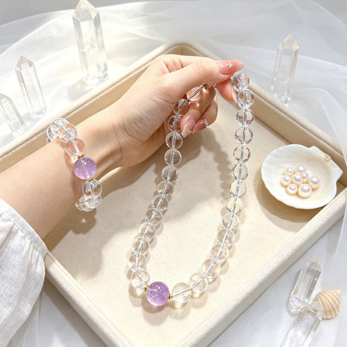 Clear quartz crystal beaded bracelet with round purple amethyst center bead in tray