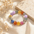 Multi-crystal gemstone bracelet with lavender, blue, orange, and clear beads on fabric