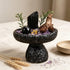 Decorative crystal bowl set with black stone, purple crystal pieces, black sphere, and pine sprigs