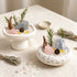 Decorative crystal bowl with rose quartz, clear crystals, gold charm, pine sprigs, and small pinecones