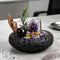 Decorative crystal bowl with amethyst cluster, black sphere, gold accents, and green pine sprigs