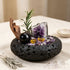 Decorative crystal bowl with purple crystal cluster, black sphere, gold accents, and greenery