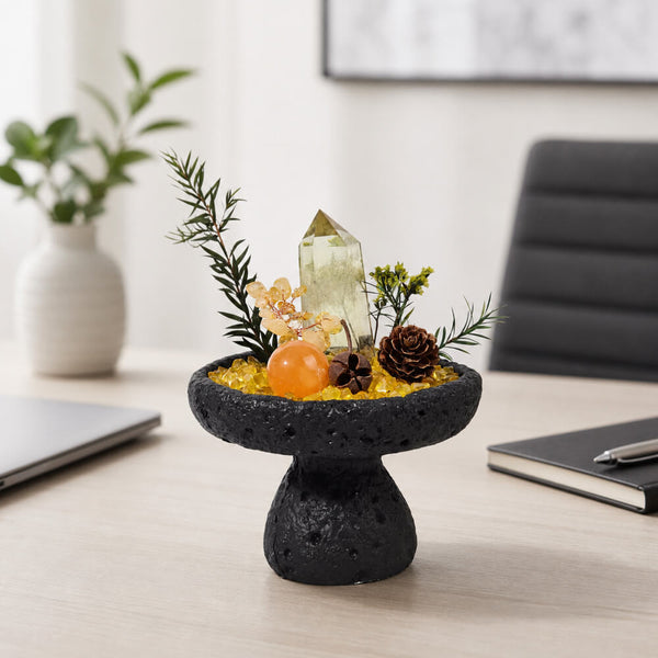 Black lava-style pedestal centerpiece with citrine tower, pine sprigs, and pinecone