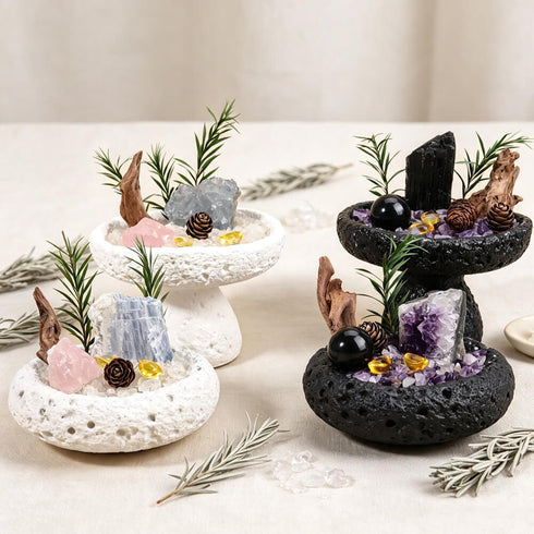 Pair of decorative crystal bowls with mixed crystals, pine sprigs, and black or white stone bases