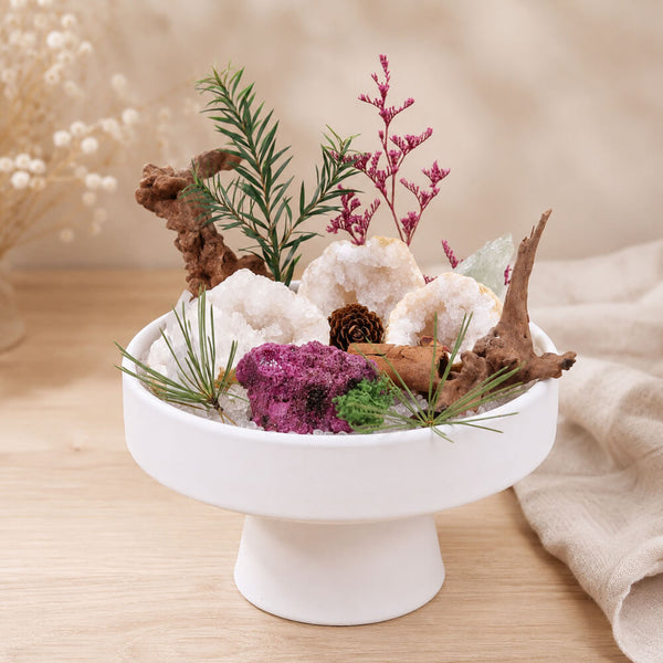 Crystal geode decor centerpiece on white pedestal, clear crystal formations with purple and dark stone