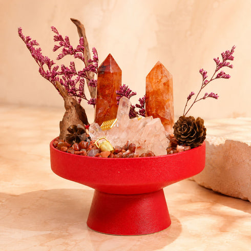 Red tabletop crystal garden centerpiece featuring orange quartz points and rose-colored crystal chunks