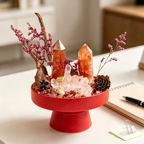 Red tabletop crystal garden centerpiece with orange quartz points, pink dried stems, and crystal pieces