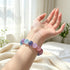Multi-color crystal bead bracelet worn on wrist, round purple, pink, blue, and rose stones