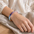 Crystal beaded bracelet worn on wrist with purple, blue, and pink round stones