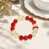 Red and clear beaded crystal bracelet featuring round stones and a charm cluster