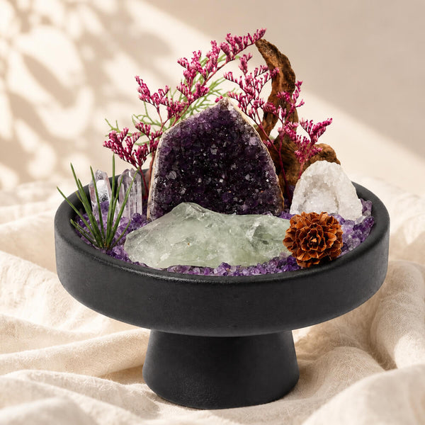 Crystal garden centerpiece in black bowl with purple amethyst rock, white crystal, and orange bloom
