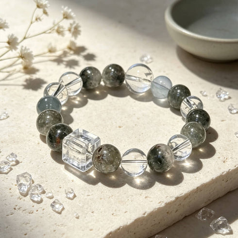 Crystal bead bracelet with dark green quartz rounds, pale blue beads, and clear cube accent