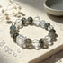 Crystal bead bracelet with dark green quartz rounds, pale blue beads, and clear cube accent