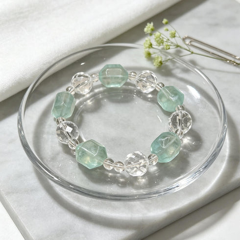 Crystal beaded bracelet with clear and light aqua faceted beads on glass dish
