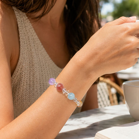 Crystal bracelet on wrist with clear beads and multicolor gemstone-like round charms