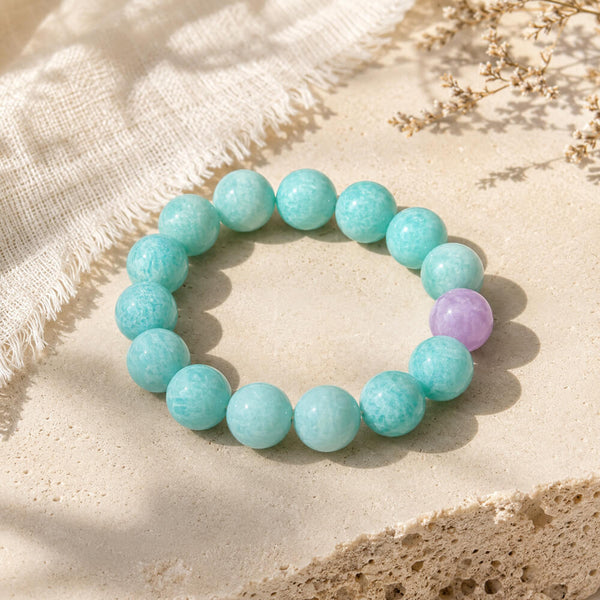 Turquoise beaded bracelet with one lavender bead, circular on light fabric