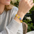 Beaded crystal bracelet on wrist with round yellow, blue, clear, and orange stones