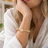 Gold and clear crystal beaded bracelet on wrist with faceted cubes and round beads