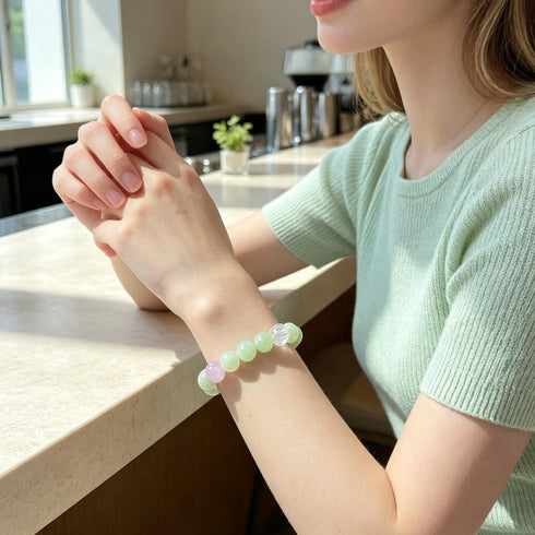 Pastel crystal bead bracelet on wrist with light green beads and clear faceted charm